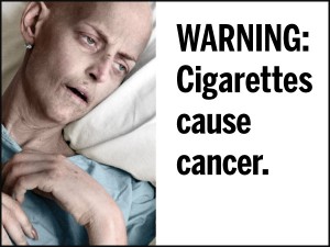 A sick person lying in bed next to a warning that cigarettes cause cancer.