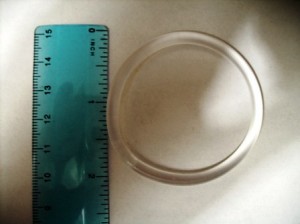 Clear circular object next to a blue ruler showing measurement in inches and centimeters.
