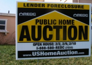 Yellow and black sign in yard reads: "Public Home Auction, Lender Foreclosure, USHomeAuction.com.