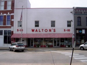 A storefront with a red and white striped awning labeled "Walton's 5-10" on a city street.