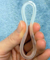 A hand holding a flexible, translucent, figure-eight shaped silicone object.