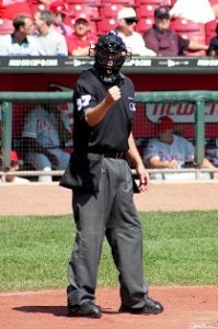 Baseball umpire on field signaling with a clenched fist during a game.