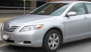 Silver sedan car parked on the street near a building, front and side view visible.