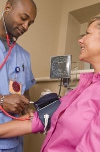Nurse checks a woman's blood pressure with a sphygmomanometer in a clinic.