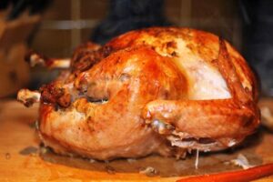 Roast turkey on a wooden surface, cooked and ready to be served.