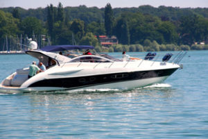 A white and black motor yacht with people on board cruising on a lake.