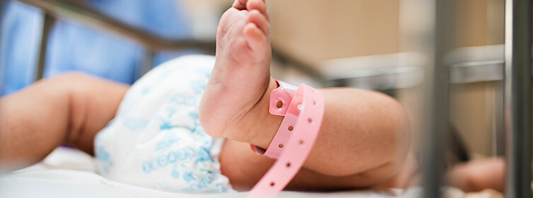 new born baby lying in hospital bed