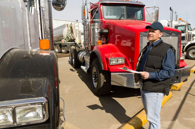 Truck driver with clipboard in hand looking at truck