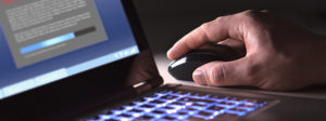 Hand using a computer mouse next to a laptop, searching for Florida truck accident attorneys.