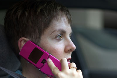 Person talking on a pink flip phone in a car, possibly calling a Florida car accident lawyer.