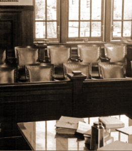 Empty jury box and table with books, evoking lawyer jury selection in a sepia-toned courtroom.