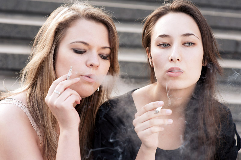 Two sad young girls smoke