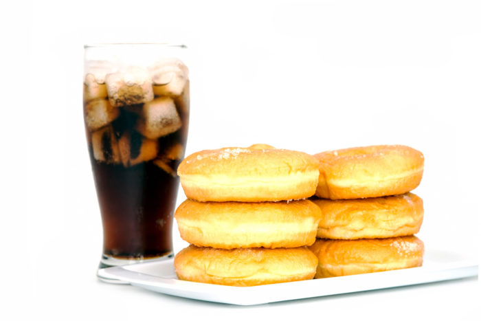 black drink (cola) and donuts and sugar over lettuce over white background