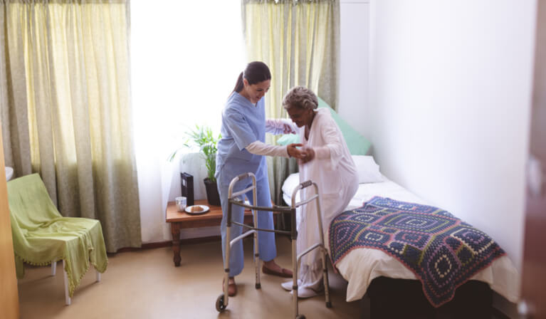 Nurse Helping Senior Stand to Avoid Bed Sores