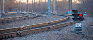 Railroad tracks with a train signal showing red near a sign marked "46" at sunset.