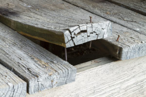 Close-up of damaged wooden boards with protruding nails, highlighting safety concerns.