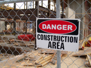 Danger Construction Area sign warns of construction hazard on a chain-link fence at the site.