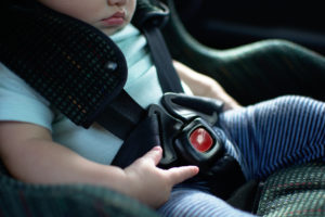 child sitting in buckled car seat