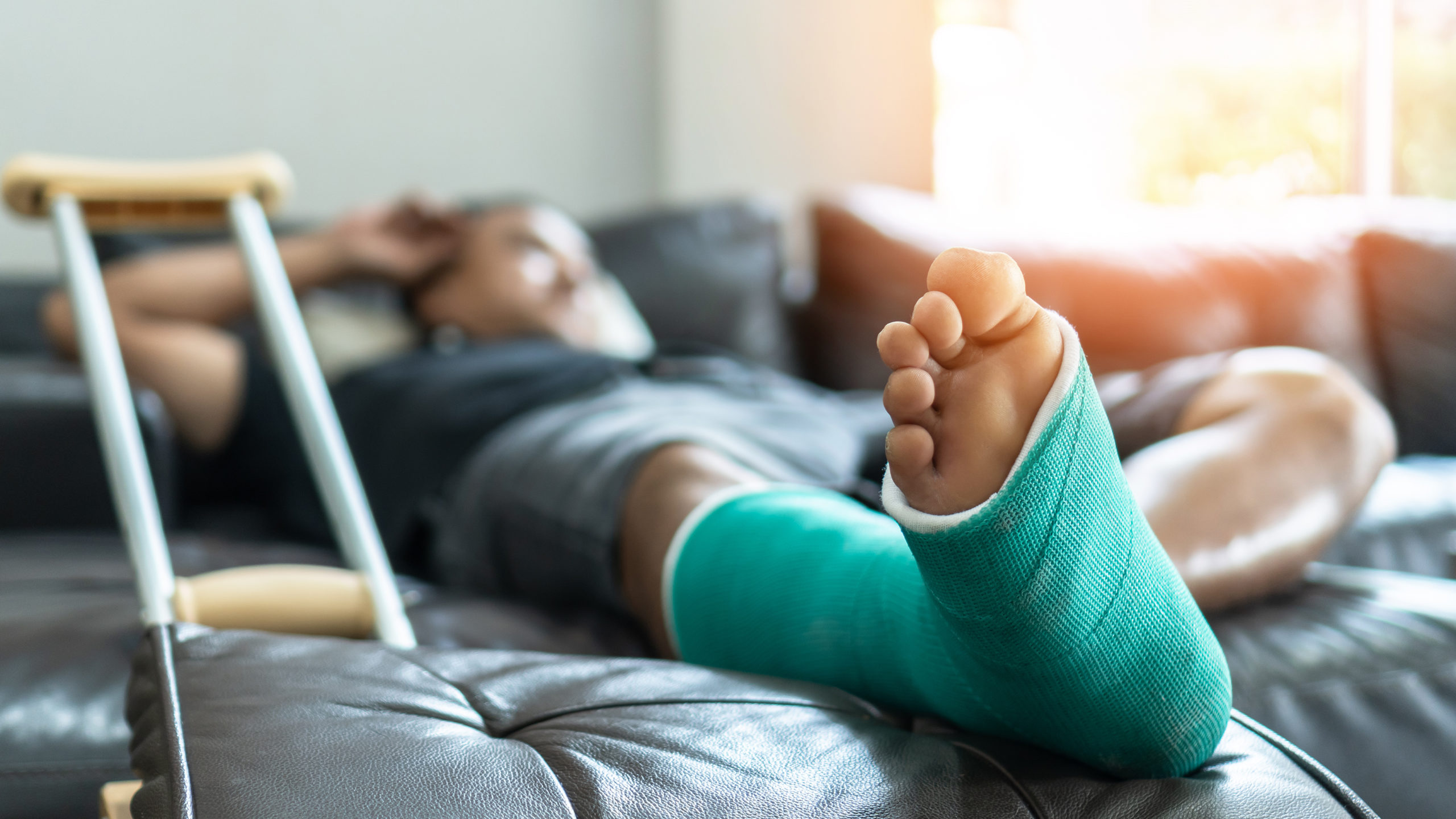 man laying on the couch with a cast on his foot and crutches