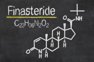 Chemical structure and formula of finasteride drawn in white chalk on a blackboard.