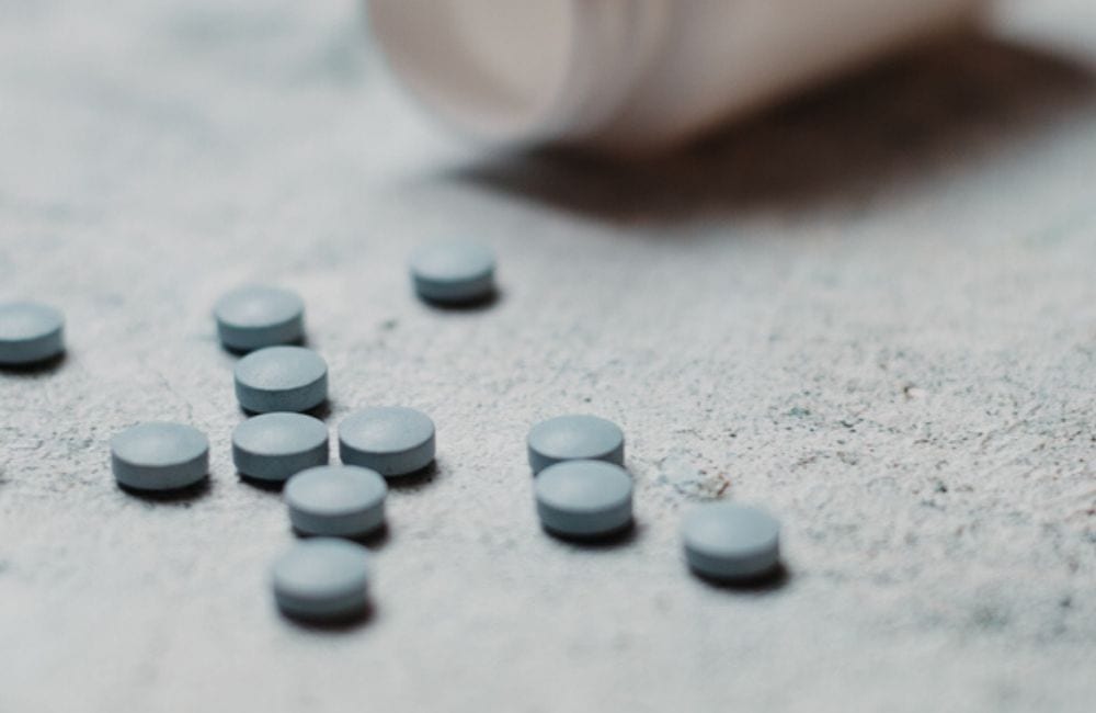A closeup of blue tablet pills spilled from a white bottle resembles the weight-loss drug Belviq. Belviq cancer concerns have prompted its recall from the market.