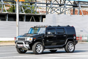 A black Hummer H2 SUV is parked on a city street near a construction site.