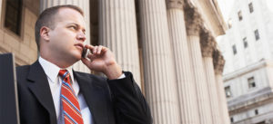 Man in suit talking on cellphone outside a large building with columns.