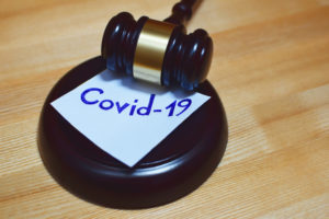 A gavel rests on a block with a paper labeled "Covid-19.