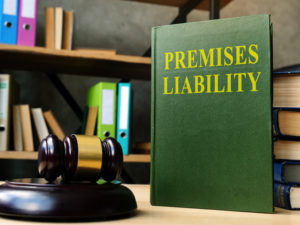 A gavel and a book titled "Premises Liability" on a desk with shelves in the background.