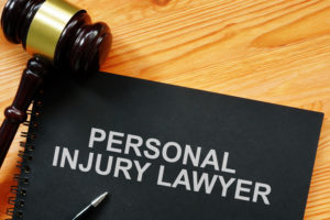 A gavel and a notebook labeled "Personal Injury Lawyer" on a wooden desk.
