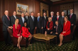A group of 15 business professionals, including a surgical stapler lawyer, pose in an office.