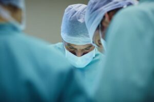 Surgeons in scrubs using tools; consult a surgical stapler lawyer for related legal issues.
