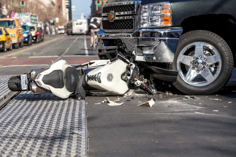 Pickup truck runs over a motorcycle in a busy street in a motorcycle accident