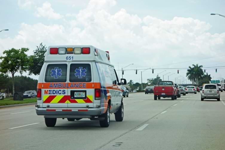 Ambulance drives down busy street in West Palm Beach Florida 