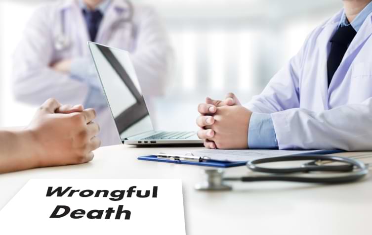 Doctors sitting at table with labtop stethoscope and wrongful death claim form 