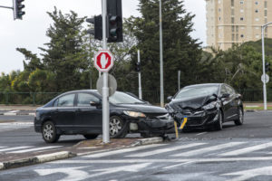 Two cars with front-end damage after a collision at a city intersection.