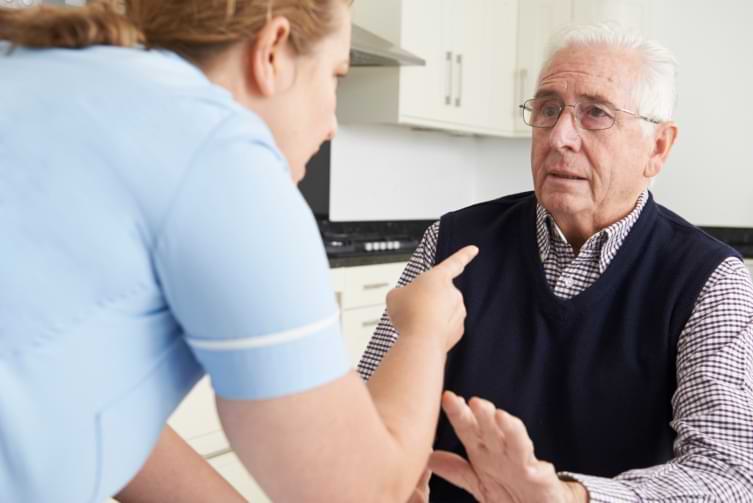 nursing home care worker aggressively pointing at elder man in chair abusively 