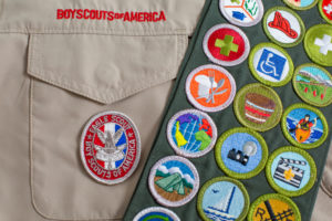 Boy Scouts uniform with Eagle Scout patch and sash displaying various merit badges.