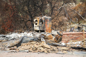 Two burned washing machines amid rubble and debris from a fire-damaged building.