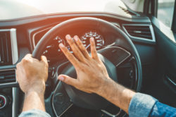 Hand man pushing car horn while driving car.