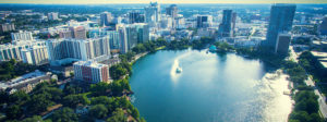 Aerial view of a city skyline with a lake and fountain in the foreground.