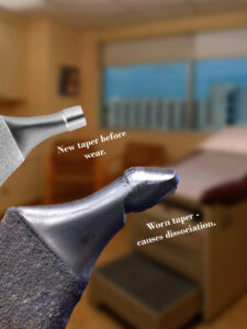 Close-up of new and worn tapers labeled to show wear and its effect, in a clinical setting.